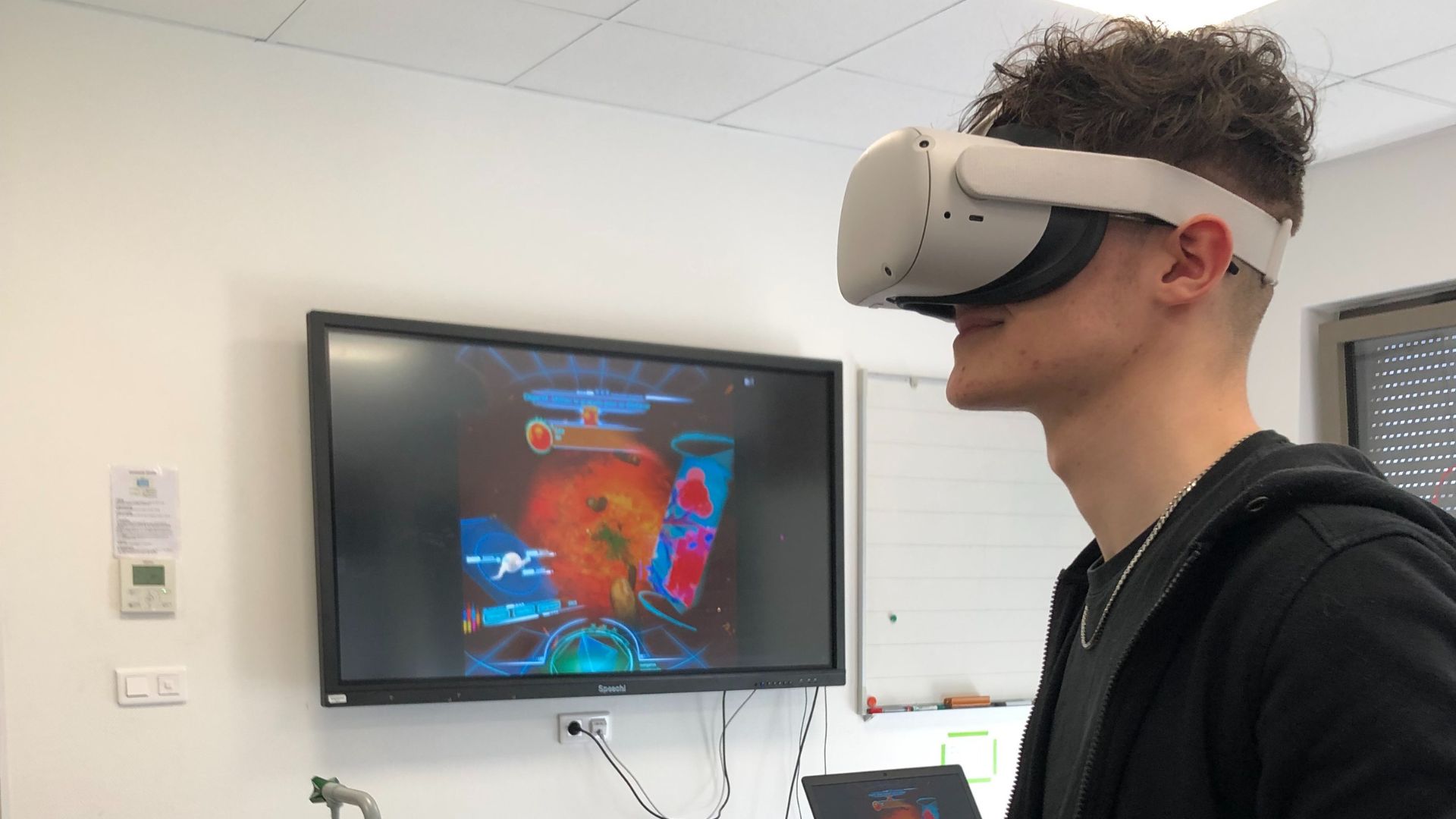 À votre santé - Un jeune avec un casque de réalité virtuelle joue avec un retour sur un écran plat.