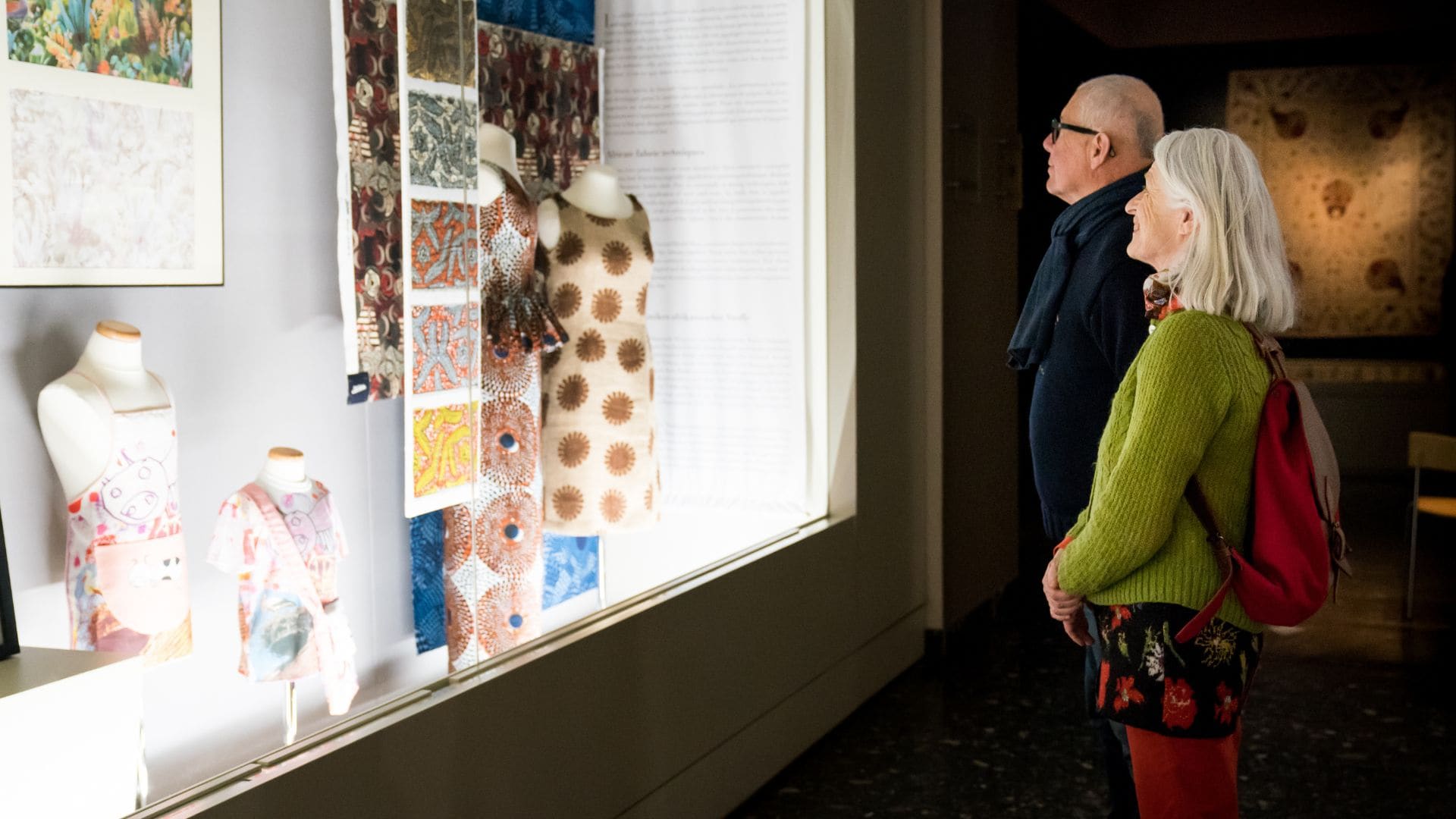 Un senior homme et une senior femme observent des éléments dans une vitrine du Musée de l'Impression sur Etoffes.