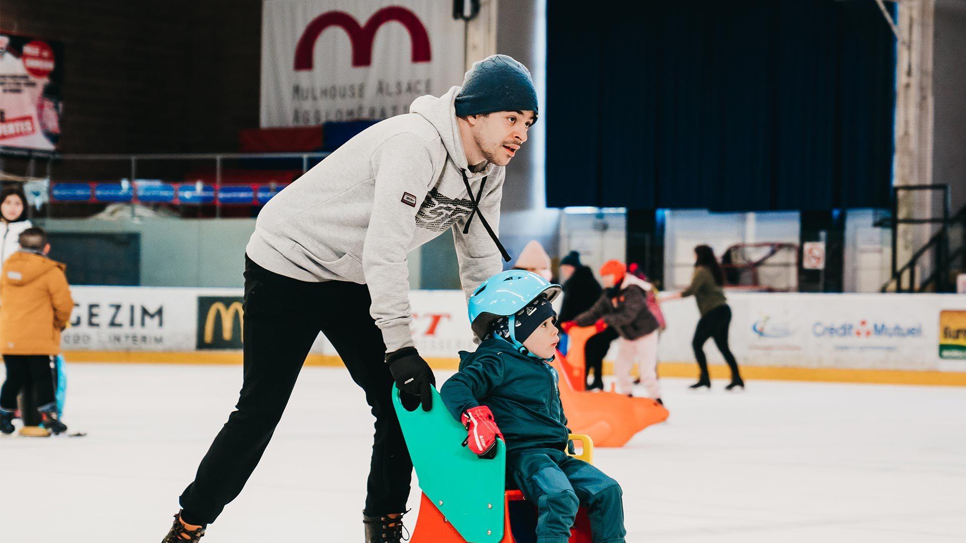 Petit garçon qui découvre la patinoire olympique à Mulhouse avec son papa