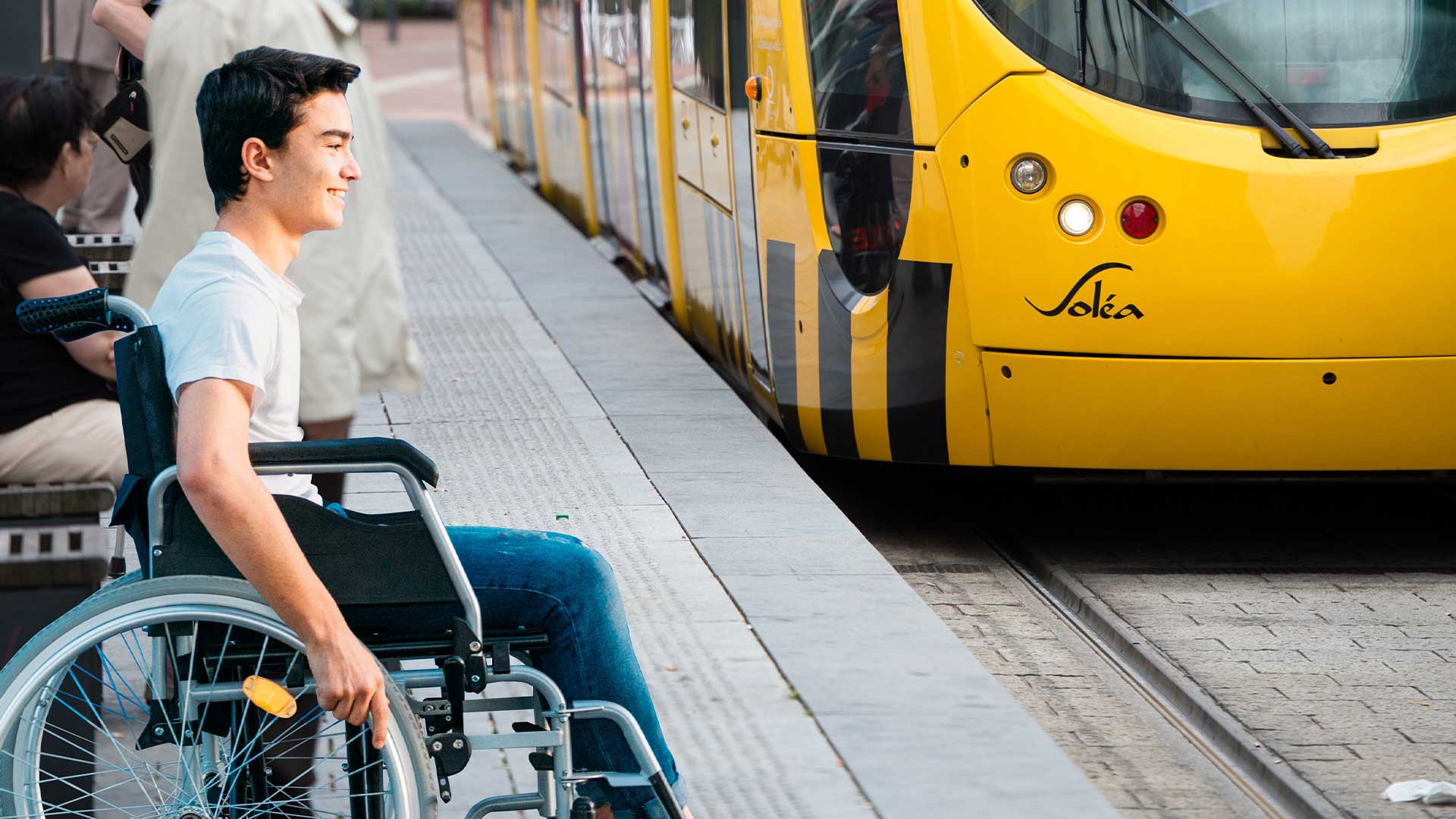 Jeune homme en fauteuil roulant qui s'apprête à rentrer dans un tramway Soléa