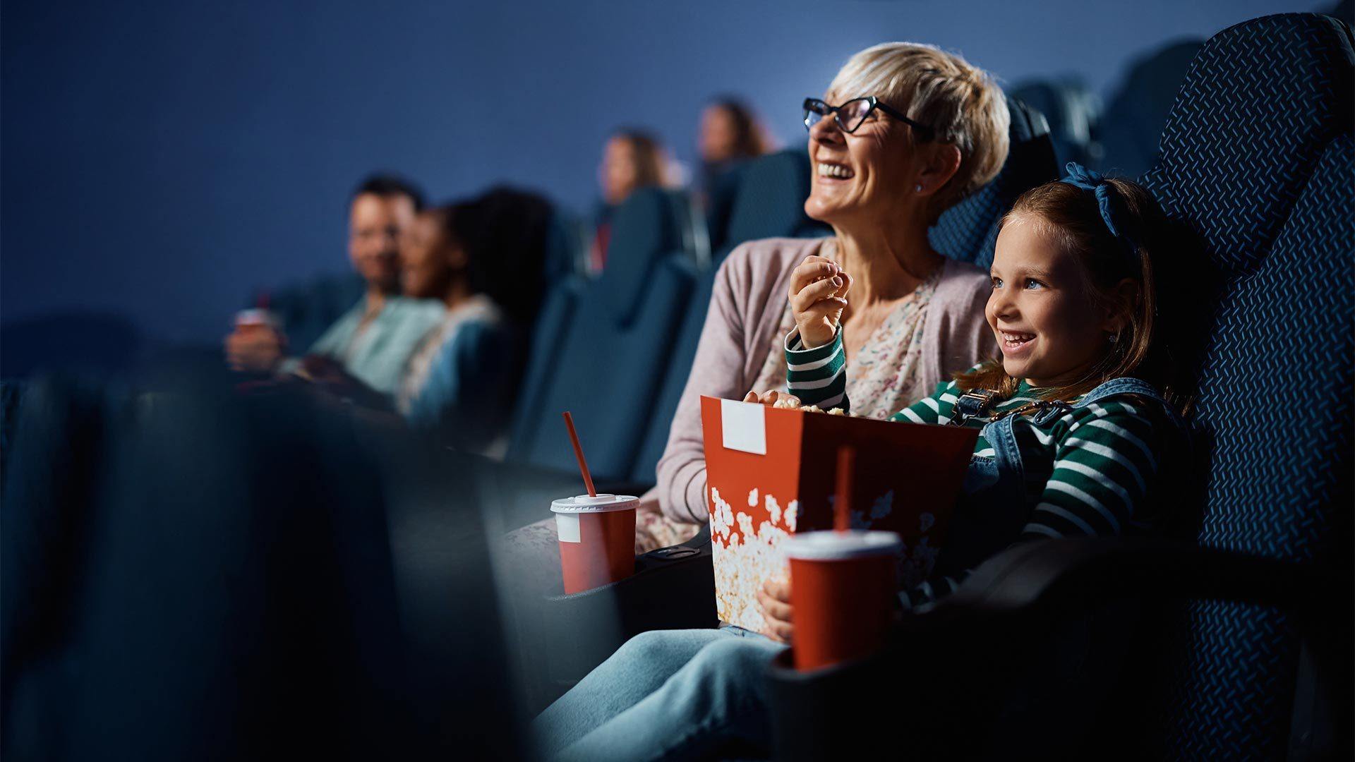 Petite-fille au cinéma qui mange du pop-corn accompagnée de sa grand-mère