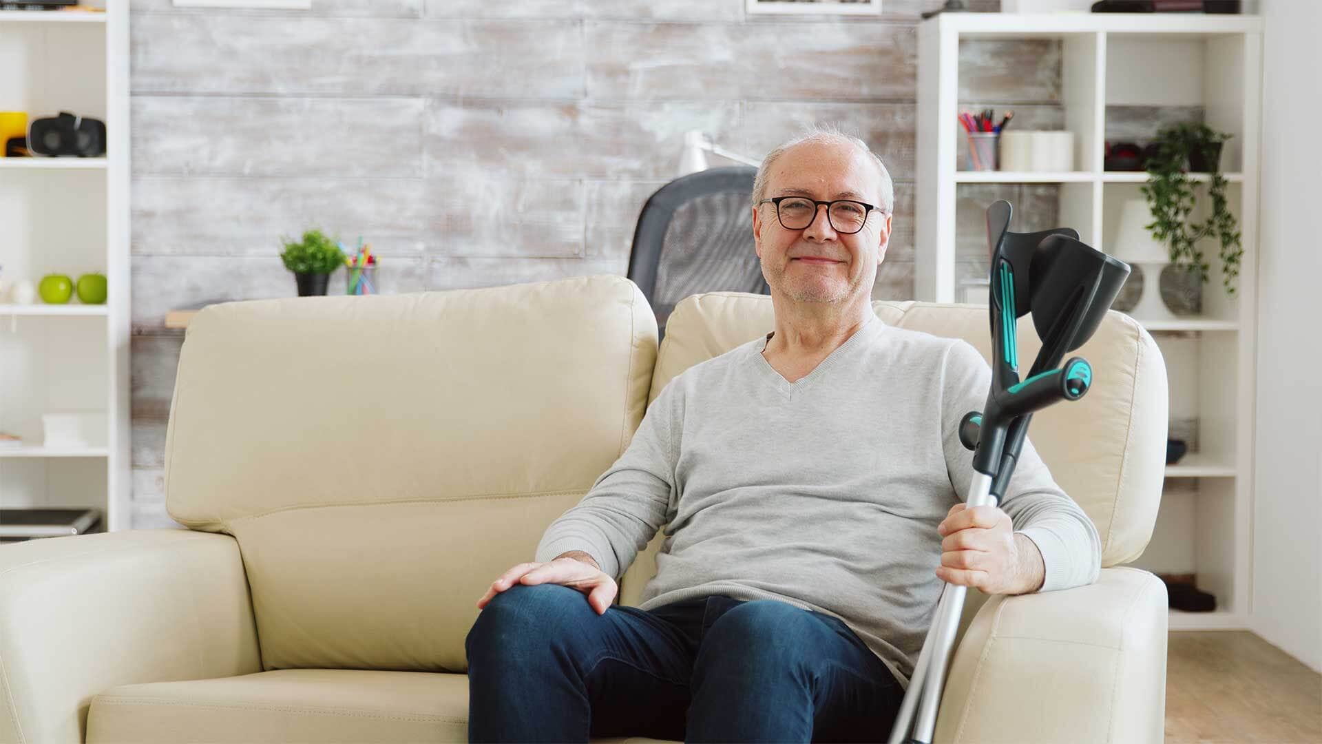 Grand-père assis sur un canapé avec des béquilles