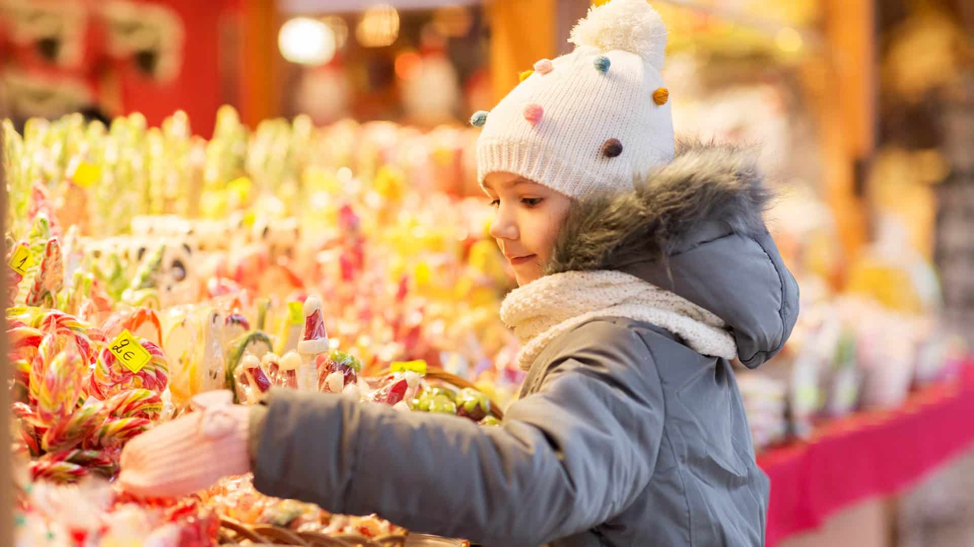 Enfant devant un stand de bonbons au marché de Noël